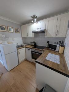 a kitchen with white cabinets and a wooden counter top at 194, Belle Aire, Hemsby - Two bed recently renovated chalet, sleeps 4, pet friendly, free Wi-Fi and bed linen and towels included in Hemsby