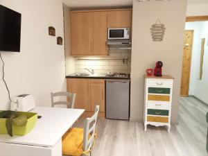 eine kleine Küche mit einem weißen Tisch, einem Tisch und Stühlen in der Unterkunft Central Plaza Cozy Studio accesso diretto alle piste in Sauze d'Oulx