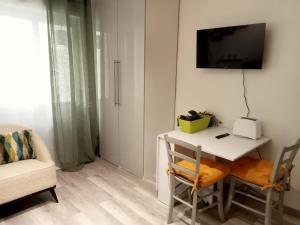 Zimmer mit einem weißen Schreibtisch und einem TV an der Wand in der Unterkunft Central Plaza Cozy Studio accesso diretto alle piste in Sauze d'Oulx