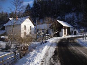 a house on a snow covered road next to a fence at Petrovický mlýn in Kasanice