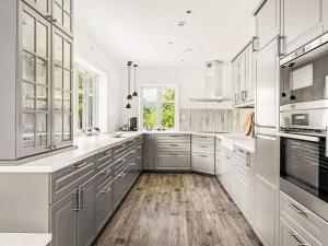 een witte keuken met houten vloeren en witte kasten bij Holiday Home Holmen by Interhome in Bakka