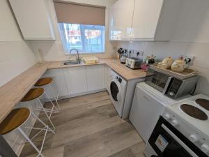 a kitchen with white cabinets and a washer and dryer at 124, Three bed two storey chalet on Bermuda holiday park, Hemsby - Sleeps 7, bed linen and towels included with onsite entertainment and further entertainment close by - includes balcony in Great Yarmouth