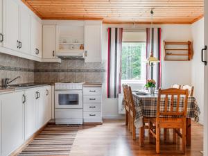 a kitchen with white cabinets and a table with chairs at Holiday Home Mörtefors by Interhome in Virserum