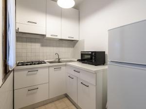 eine Küche mit weißen Schränken und einer Spüle und einer Mikrowelle in der Unterkunft Holiday Home Villa 19 by Interhome in SantʼAmanza