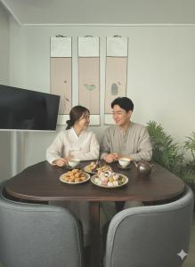 a man and woman sitting at a table with plates of food at Slow accommodation,Free parking,kspo dome,Kangdong Sacred Heart Hospital,Seoul Asan Hospital,COEX,Lotte World Tower,kspo in Seoul
