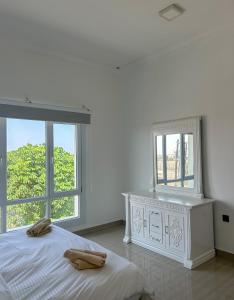a white bedroom with a bed and two windows at VILLA seeb 2 MIN walk to the beach in Seeb