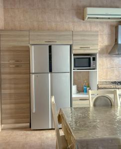 a white refrigerator in a kitchen with a table at VILLA seeb 2 MIN walk to the beach in Seeb