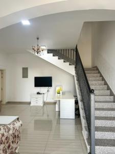 a living room with a staircase and a television at VILLA seeb 2 MIN walk to the beach in Seeb