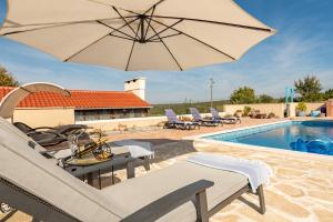 a patio with an umbrella and chairs and a pool at Stone villa Jurenda with pool in Debeljak