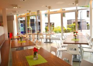 a restaurant with tables and chairs with flowers on them at Wilhelm Kliewer Haus in Mönchengladbach