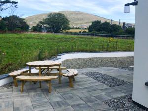 une table de pique-nique et deux bancs sur une terrasse dans l'établissement Holiday Home Bell View - TR3 Holiday Home Sheeps Head by Interhome, à Kilcrohane