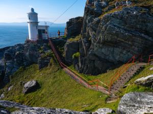 un phare sur le flanc d'une falaise rocheuse dans l'établissement Holiday Home Bell View - TR3 Holiday Home Sheeps Head by Interhome, à Kilcrohane