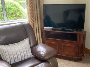 une chaise en cuir marron assise devant une télévision dans l'établissement Holiday Home Lisheenbawn Farmhouse Farranfore by Interhome, à Castleisland