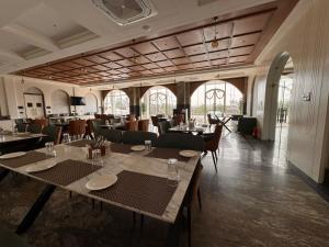 a dining room with tables and chairs and windows at Hotel Mumbai House Pithampur in Dhār +26 photos