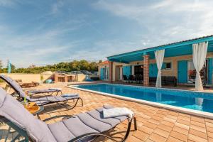a swimming pool with chairs and a house at Stone villa Jurenda with pool in Debeljak