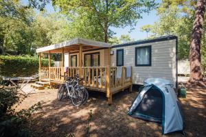 a tiny house with a tent and bikes parked next to it at Camping Les Pins de la Coubre in Les Mathes