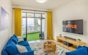 a living room with a blue couch and a tv at Elna's Baobab Waves - 2BR and 3BR Beachfront Nyali in Mombasa
