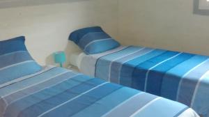 twee bedden in een slaapkamer met blauwe en witte lakens bij Les Hirondelles du Cap in Besnard