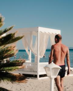 a man walking on the beach with a gazebo at Palace Hotel & SPA in Durrës