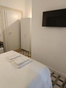 a white bedroom with a bed with two towels on it at Residence e appartamenti Rosaroll in Naples
