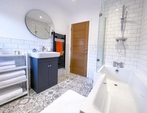 a white bathroom with a tub and a sink and a mirror at New! 1BR in Horsemarket in Darlington