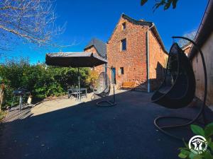 un edificio con sombrilla, mesa y sillas en La Prunille, en Pruines