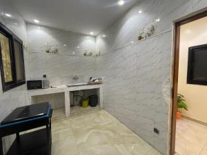 a white tiled bathroom with a sink and a counter at Studio meublé de luxe in Dakar