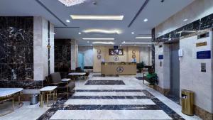 a lobby with tables and chairs in a building at فندق البارون الذهبي in Az Zāhir
