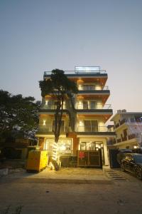un grand bâtiment avec un arbre devant dans l'établissement Royal Raven Hotel & Banquet' Greater Noida, à Greater Noida