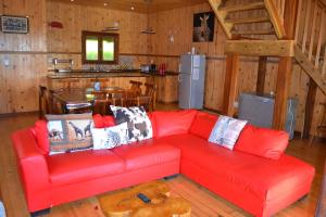 a red couch in a living room with a kitchen at Onda Azul Main House in Ponta do Ouro