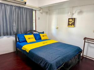 a bedroom with a bed with blue and yellow pillows at Dengba Hostel - Loikroh Chiangmai in Ban Hua Phrong
