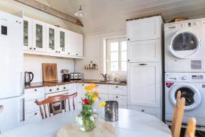 a kitchen with white cabinets and a table with flowers at Toftenäs gästhus in Toftenäs