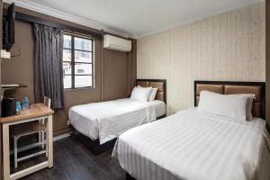 a hotel room with two beds and a window at HOTEL JJH Aliwal in Singapore
