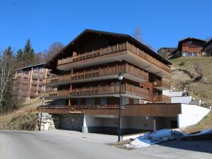 ein großes Gebäude mit Holzbalkonen auf einem Hügel in der Unterkunft Appartement 3 pièces avec garage, terrasse, proche pistes et commerces à Arâches-la-Frasse - FR-1-572-250 in Arâches-la-Frasse