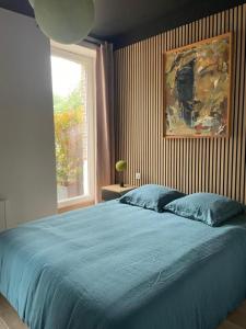 a bedroom with a large blue bed with a window at La Chênaie - Suites individuelles dans un domaine d'art contemporain et nature in Gien