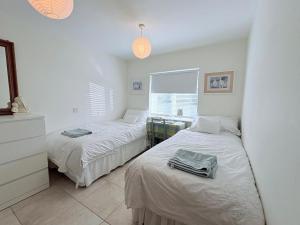 two beds in a room with white walls at Spring Grange Cottage in Winscombe