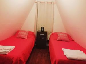 twee bedden in een kleine kamer met rode lakens bij Husky casa de montaña in Ushuaia
