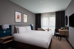a hotel room with a large white bed and a desk at George Limerick Hotel in Limerick