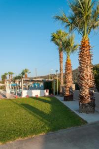 two palm trees in a park with a building at Vergina Sun in Faliraki