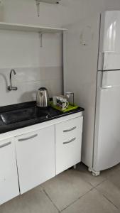 a white kitchen with a sink and a refrigerator at Quarto na praia da Pinheira in Palhoça +5 photos