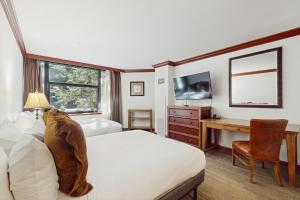 a bedroom with a bed and a desk and a television at Everline Resort & Spa 317 in Olympic Valley