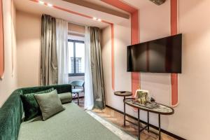 a living room with a green couch and a flat screen tv at THE STEPS Hotel - by Eitch Collection in Rome