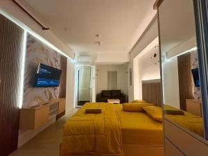 a bedroom with a large yellow bed and a tv at Apartemen Gunung Putri by Maknyoss Rooms in Pabuaran Satu