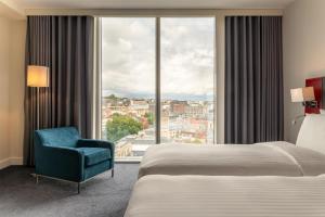 a hotel room with a bed and a chair and a large window at Radisson Blu Hotel, Bristol in Bristol +157 photos