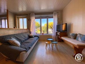 a living room with a couch and a tv at Le Square des Fleurs in Le Nayrac