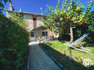 a garden with a white chair in front of a house at Le Square des Fleurs in Le Nayrac
