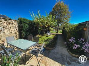 a patio with a table and chairs in a garden at Le Square des Fleurs in Le Nayrac