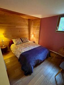 Un dormitorio con una cama con una pared de madera. en Meublés Les Charmettes, en Chambéry