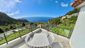 un balcon avec une table et des chaises et une vue sur l'océan dans l'établissement Casa Borboleta, à Arco da Calheta