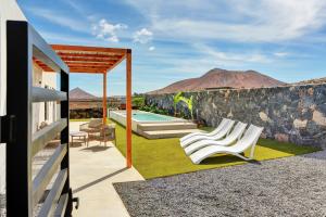 a patio with white chairs and a swimming pool at ISLAND WEEK Fuerteventura in La Oliva